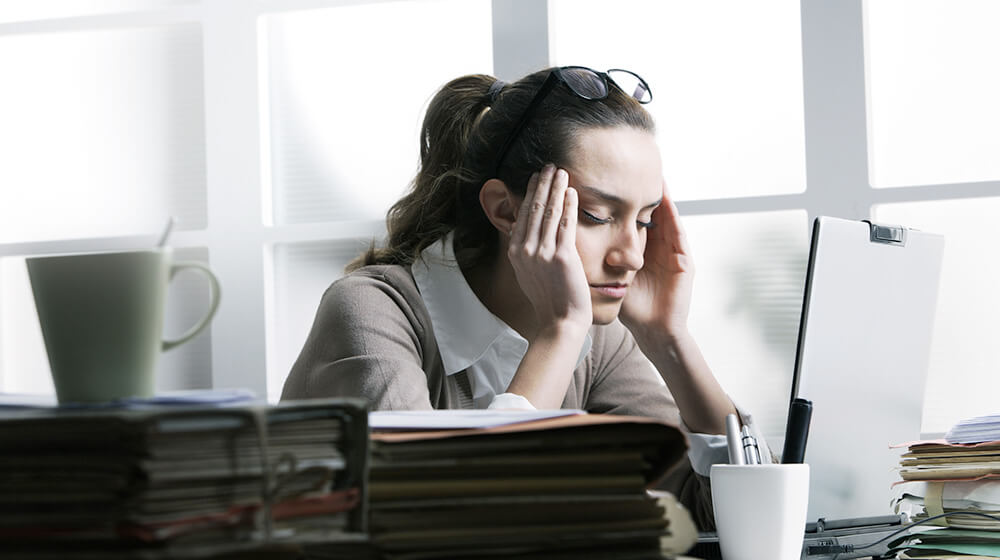 Women in front of computer rubbing  her temples